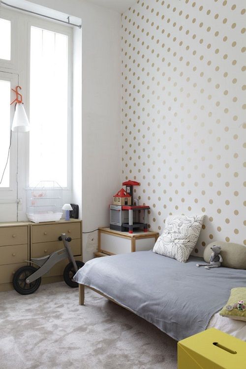 Pared de lunares dorados en habitación infantil